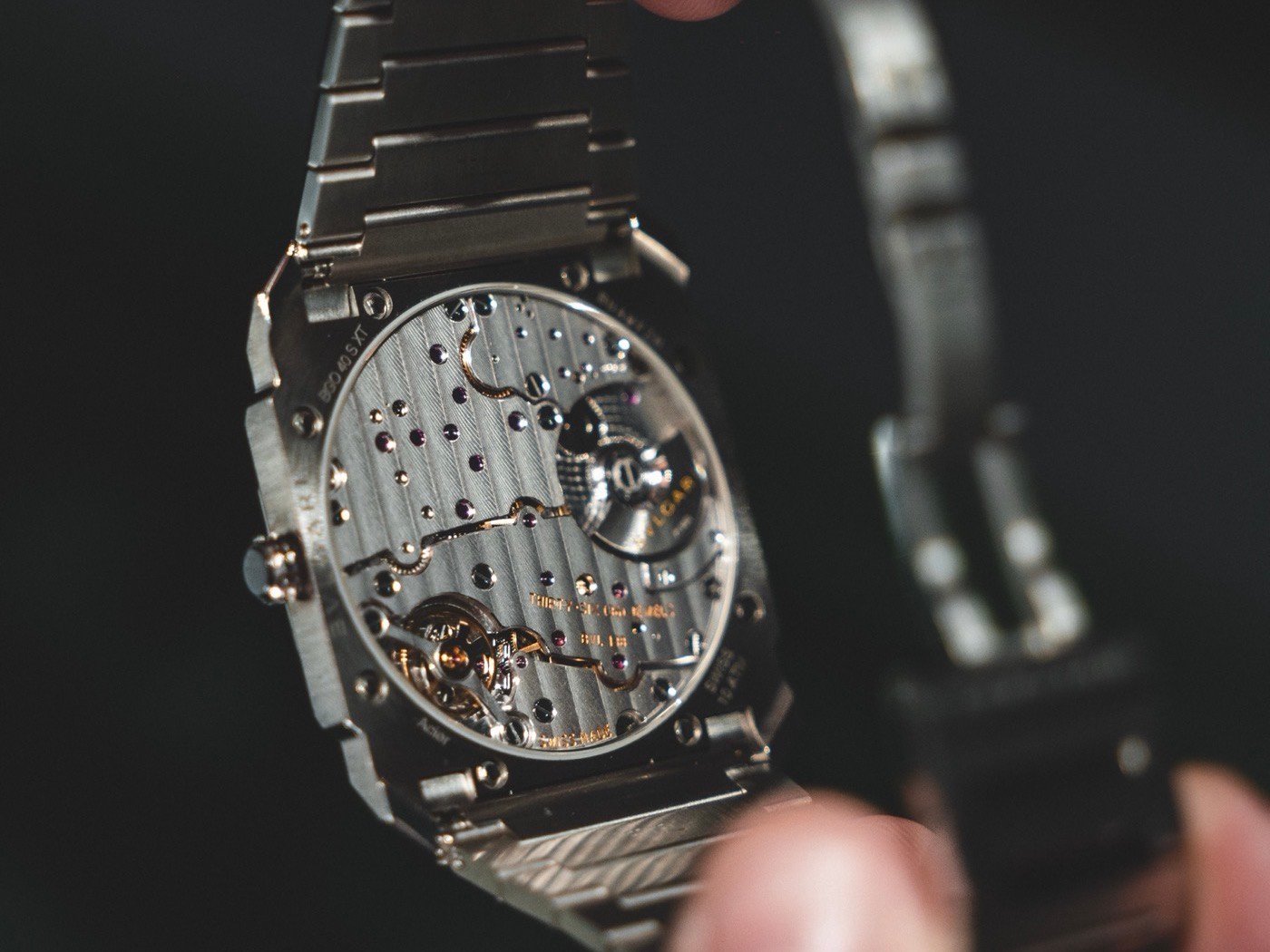 Il fondello aperto di un orologio automatico, con il movimento a vista, tenuto in mano in laboratorio
